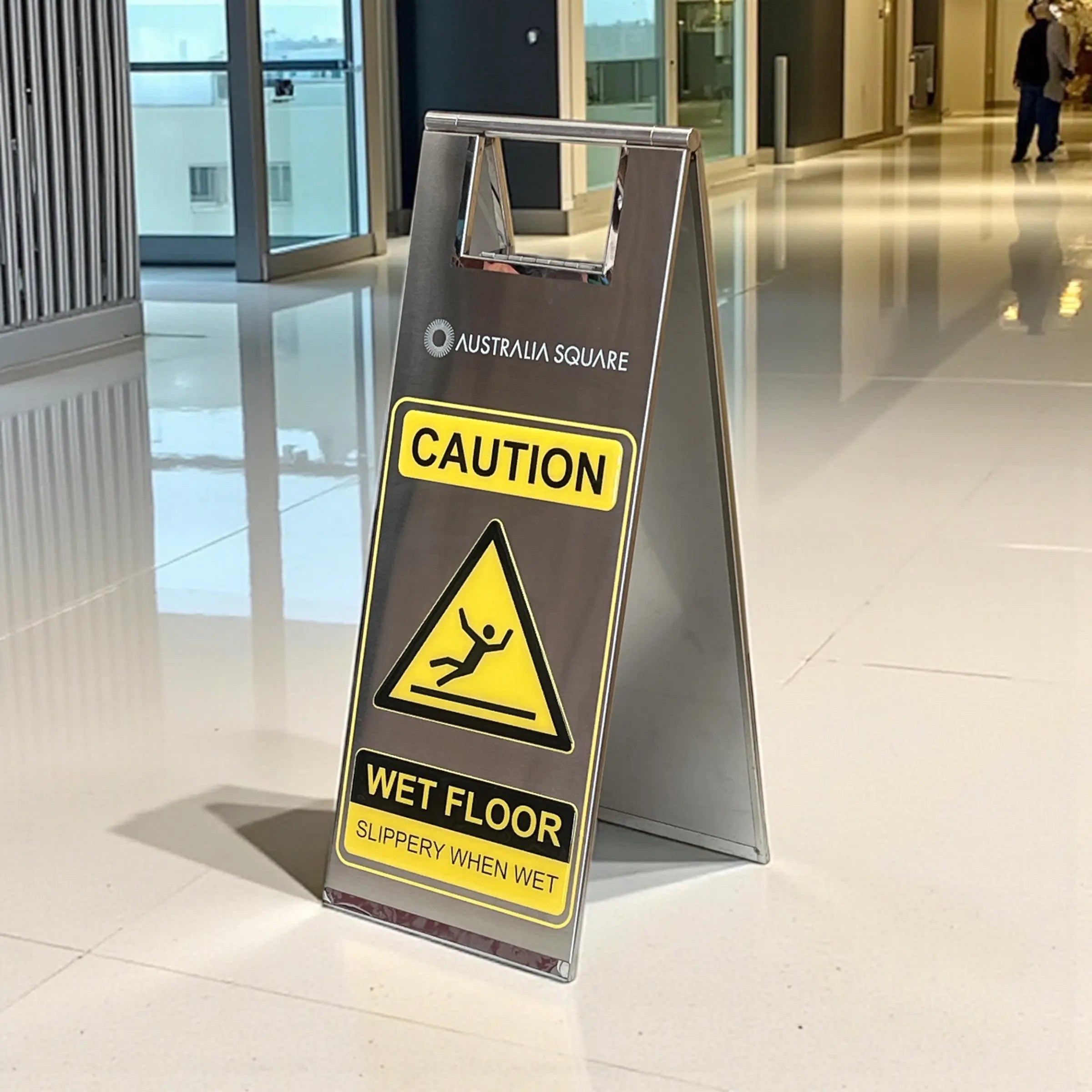 Stainless steel wet floor safety sign in a commercial building entrance
